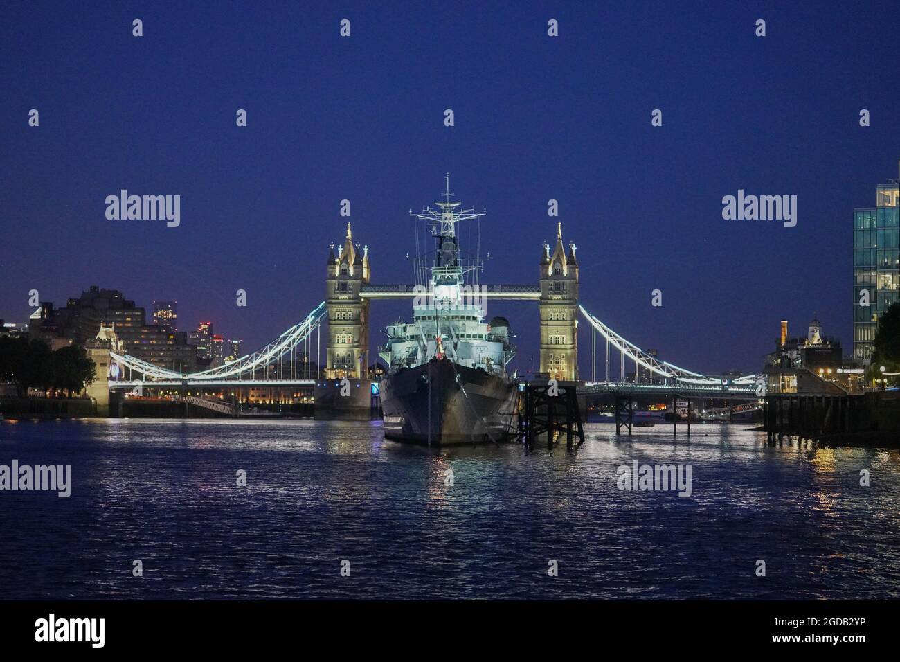 Vue sur le HMS Belfast avec Tower Bridge en arrière-plan, prise d'un bateau sur la Tamise lors d'une croisière en soirée. Date de la photo : vendredi 6 août Banque D'Images