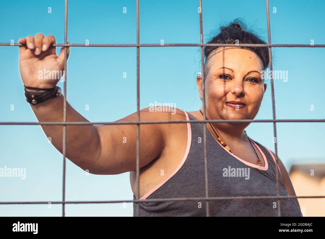 Femme d'âge moyen positive avec coupe de cheveux Cherokee. Regarder à travers le fil Banque D'Images