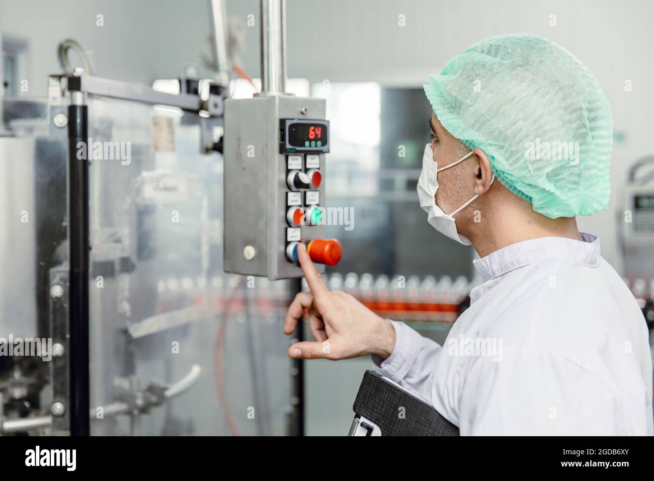 Les employés qui travaillent utilisent la machine de contrôle dans l'usine alimentaire d'hygiène. Banque D'Images