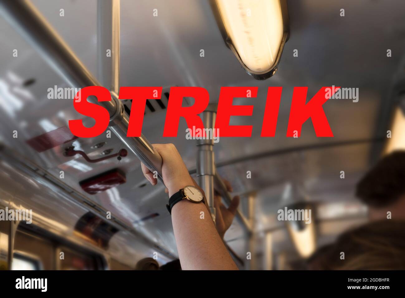 Texte allemand Streik (signifiant grève) et une main tenant sur le bar dans un train de métro pendant l'heure de pointe, focus sélectionné, profondeur de champ étroite Banque D'Images