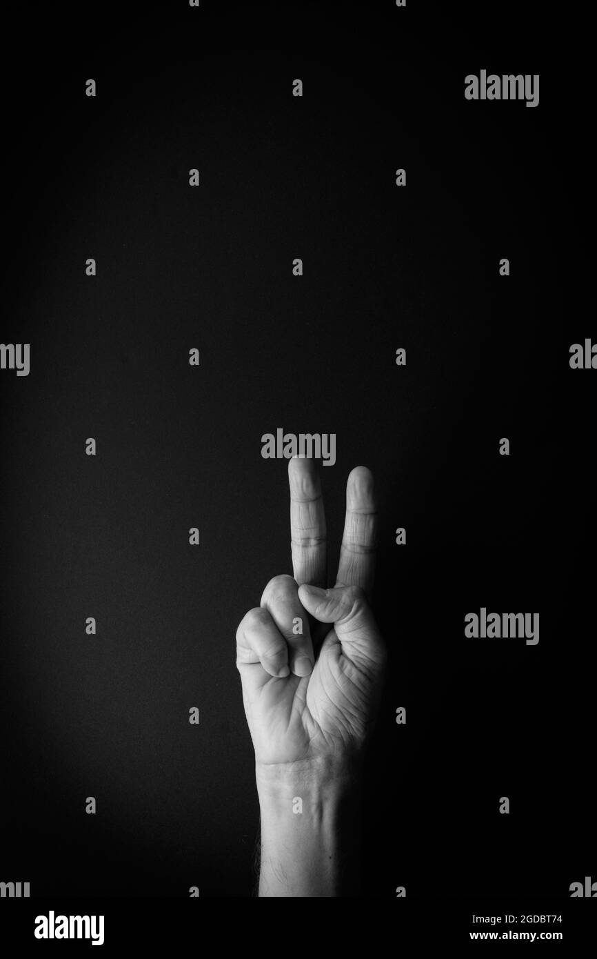 Image spectaculaire en noir et blanc de la main masculine montrant le langage des signes numéro deux sur fond noir avec espace de copie vide pour les éditeurs Banque D'Images