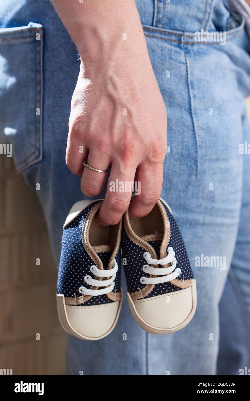 Chaussures pour enfants de petite taille dans la main de femme caucasienne, vue rapprochée Banque D'Images