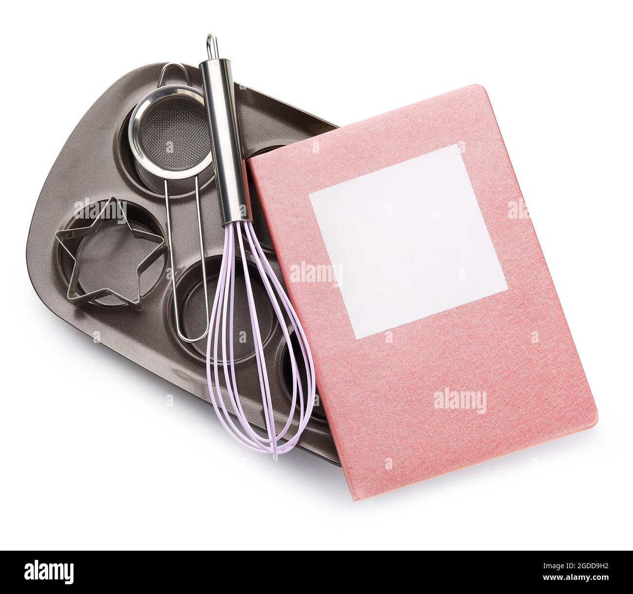 Livre de recettes avec moule à pâtisserie et fouet sur fond blanc Banque D'Images