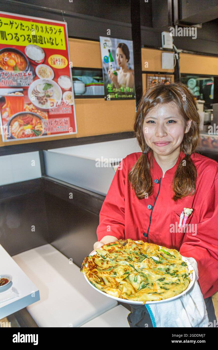 Tokyo Japon, restaurant Ikebukuro, intérieur intérieur asiatique femme orientale, serveuse employée de serveur servant des plats à pizza japonais, Banque D'Images
