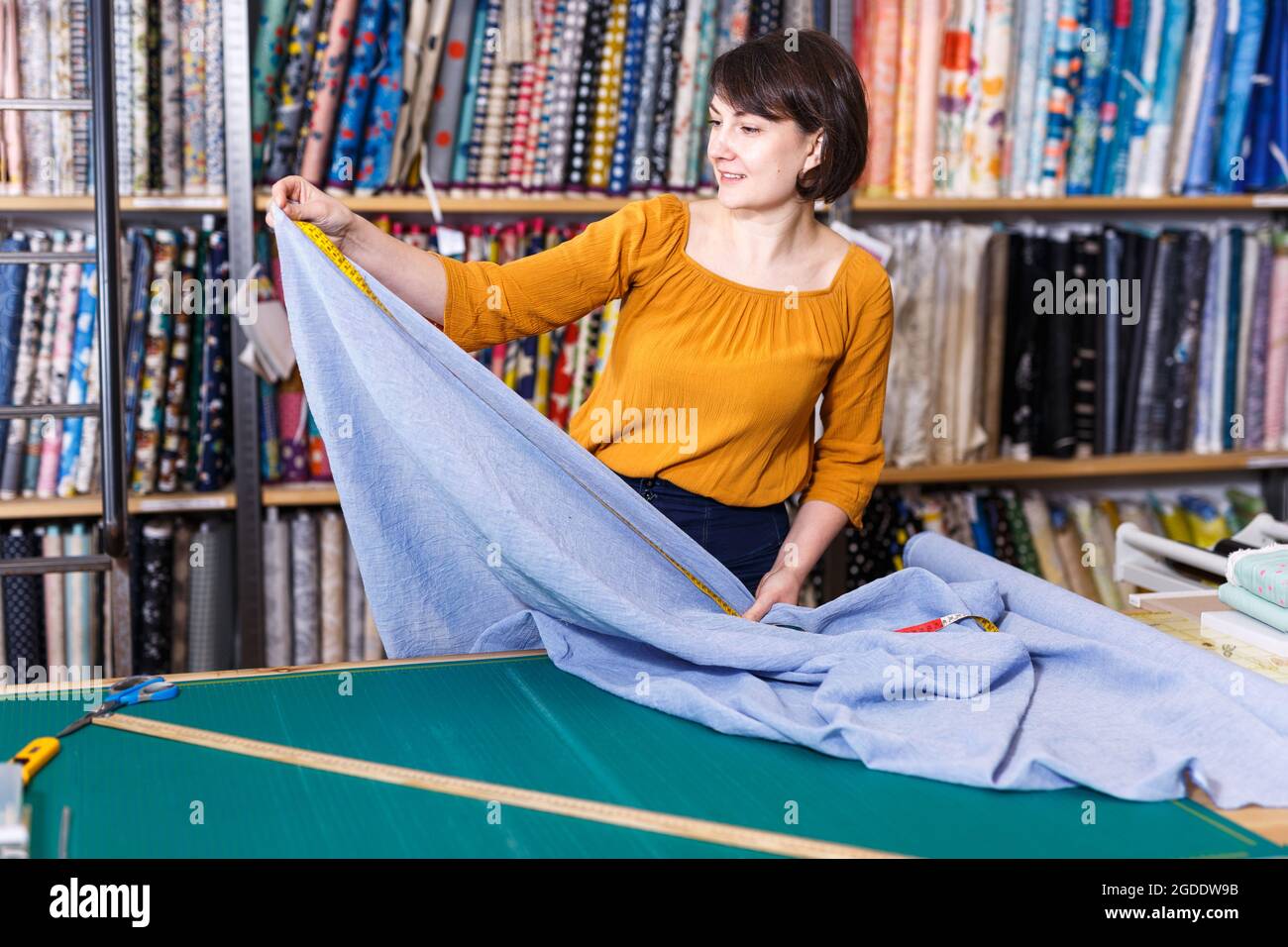 Femme vendeur mesurant et coupant des morceaux de textile Banque D'Images