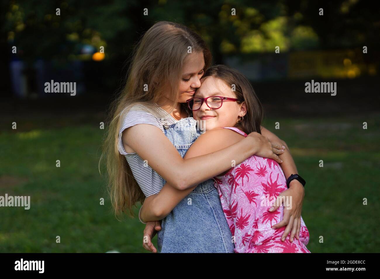 Une petite fille embrasse sa sœur aînée. Amour et amitié. Concept de famille heureux. Banque D'Images