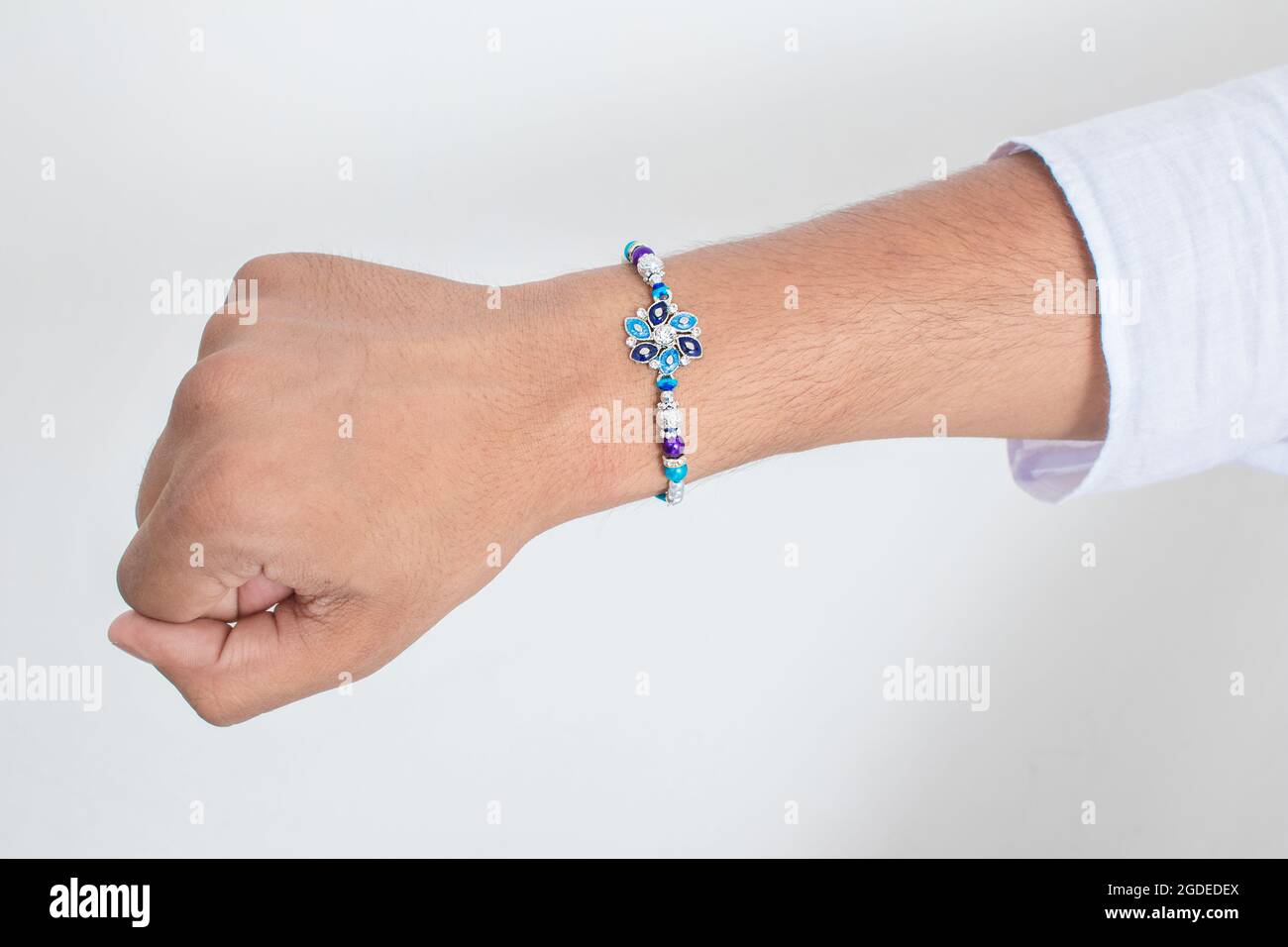 Main portant beau bleu diamant design rakhi à l'occasion de raksha bandhan sur fond blanc. Festival indien célébré en Inde à expre Banque D'Images Main portant beau bleu diamant design rakhi à l'occasion de raksha bandhan sur fond blanc. Festival indien célébré en Inde à expre Banque D'Images