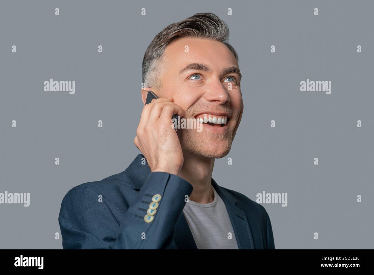 Un homme heureux avec un sourire crasseux communiquant par téléphone intelligent Banque D'Images