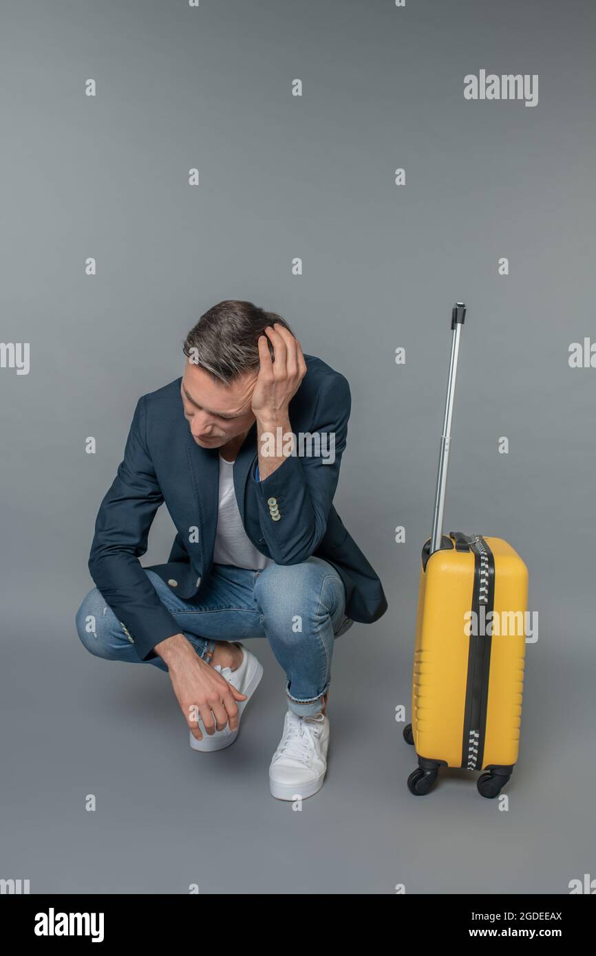 Un triste homme s'est accrouillé près de sa valise Photo Stock - Alamy