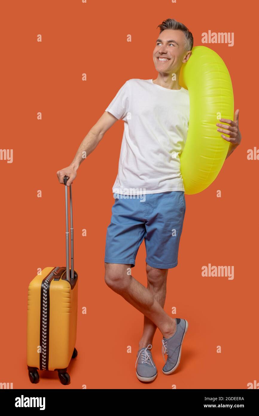 Homme avec anneau gonflable et valise Banque D'Images