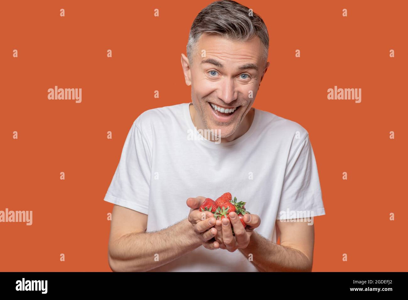 Homme heureux tenant des fraises dans ses paumes Banque D'Images