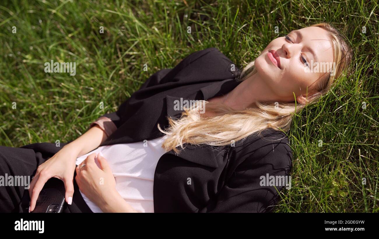 Femme d'affaires couchée sur l'herbe dans le parc Banque D'Images
