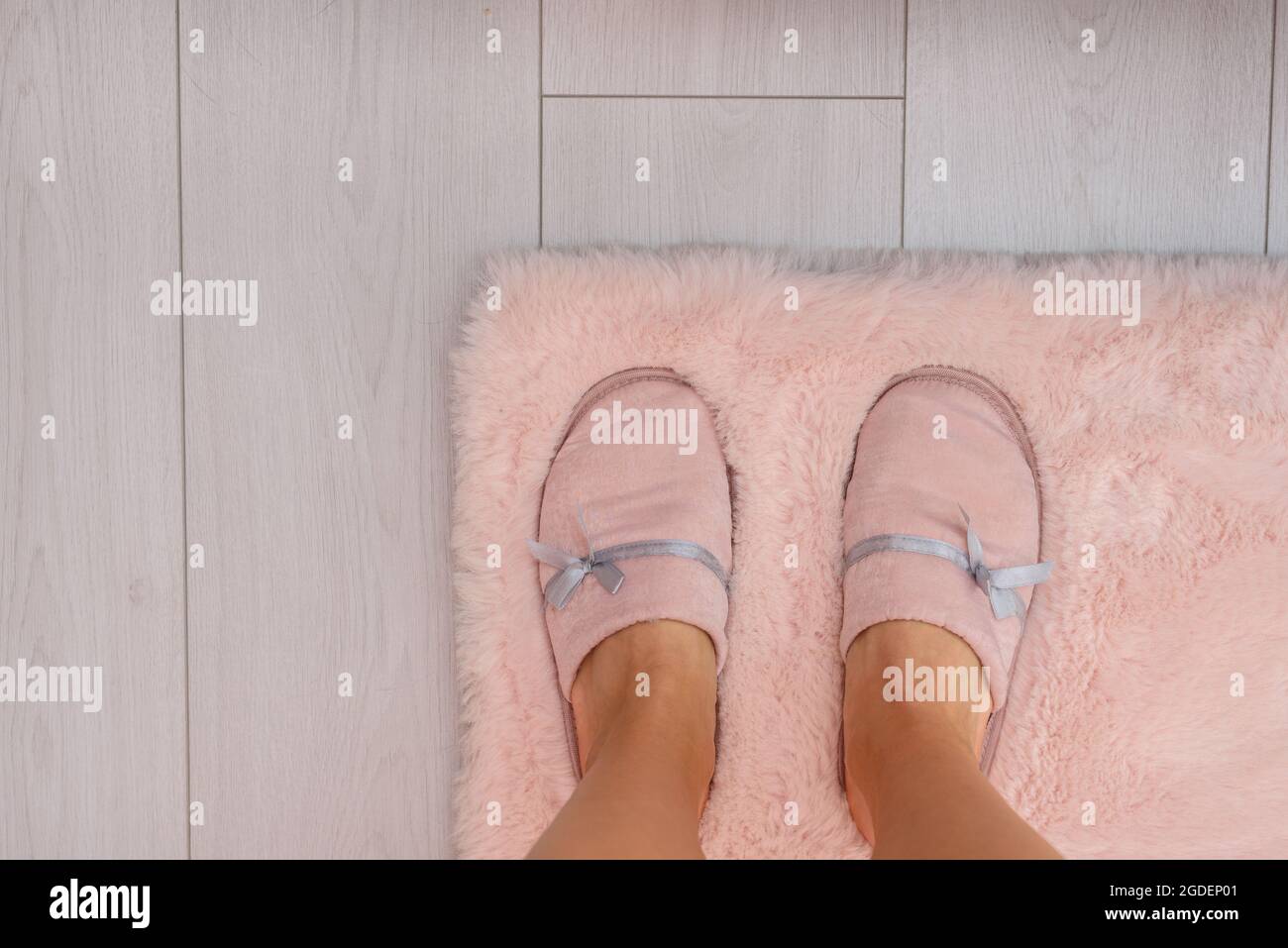 Pieds en pantoufles roses sur moquette en fourrure et sol blanc Banque D'Images