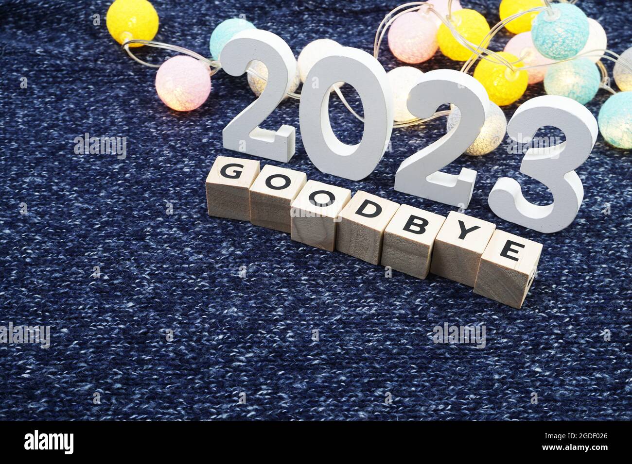 Lettre à l'alphabet Au revoir 2023 avec boule en coton à DEL sur fond de tissu tricoté bleu Banque D'Images