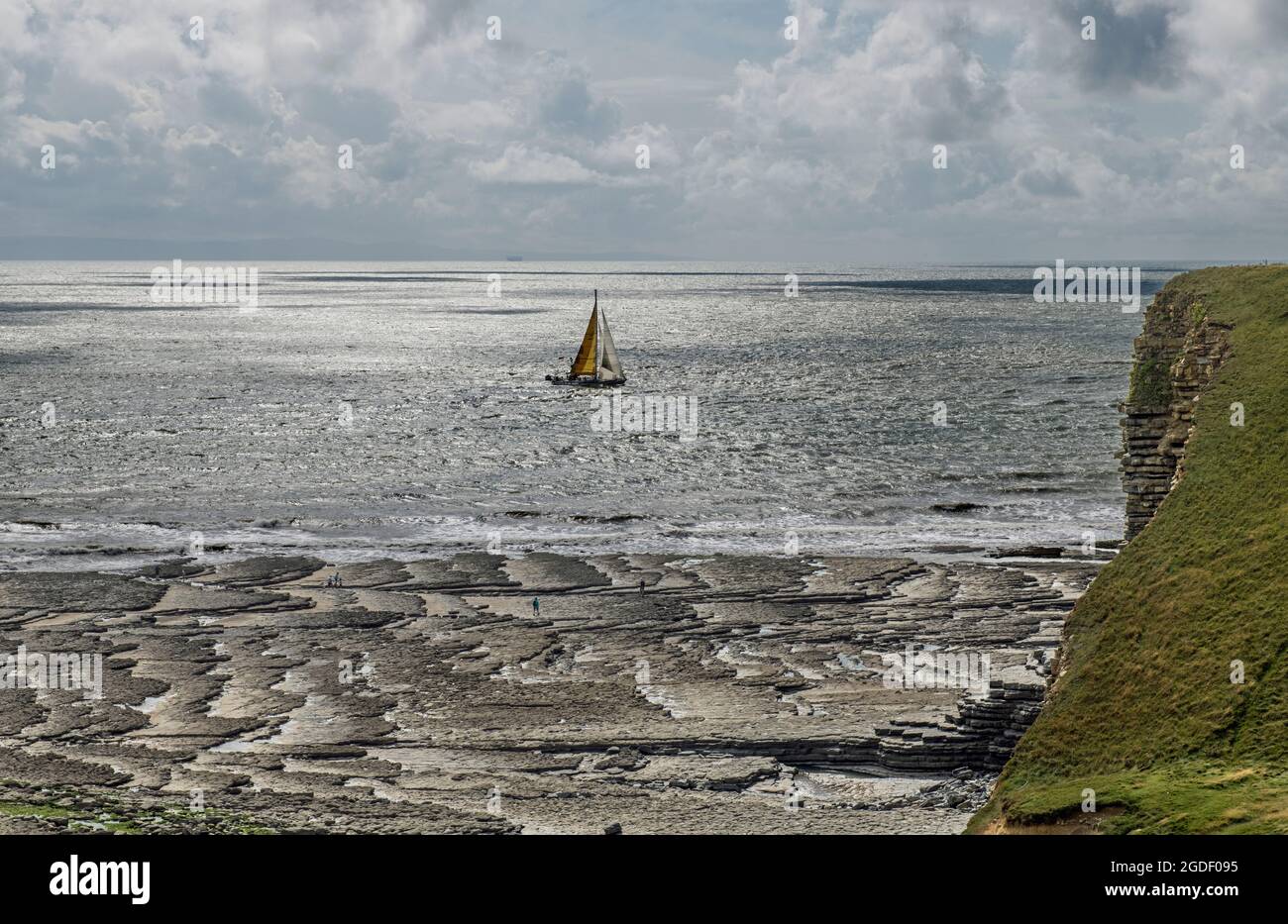 Un yacht passant devant la plage de Nash point sur la côte du patrimoine de Glamourgan, au sud du pays de Galles, un après-midi d'août. Banque D'Images