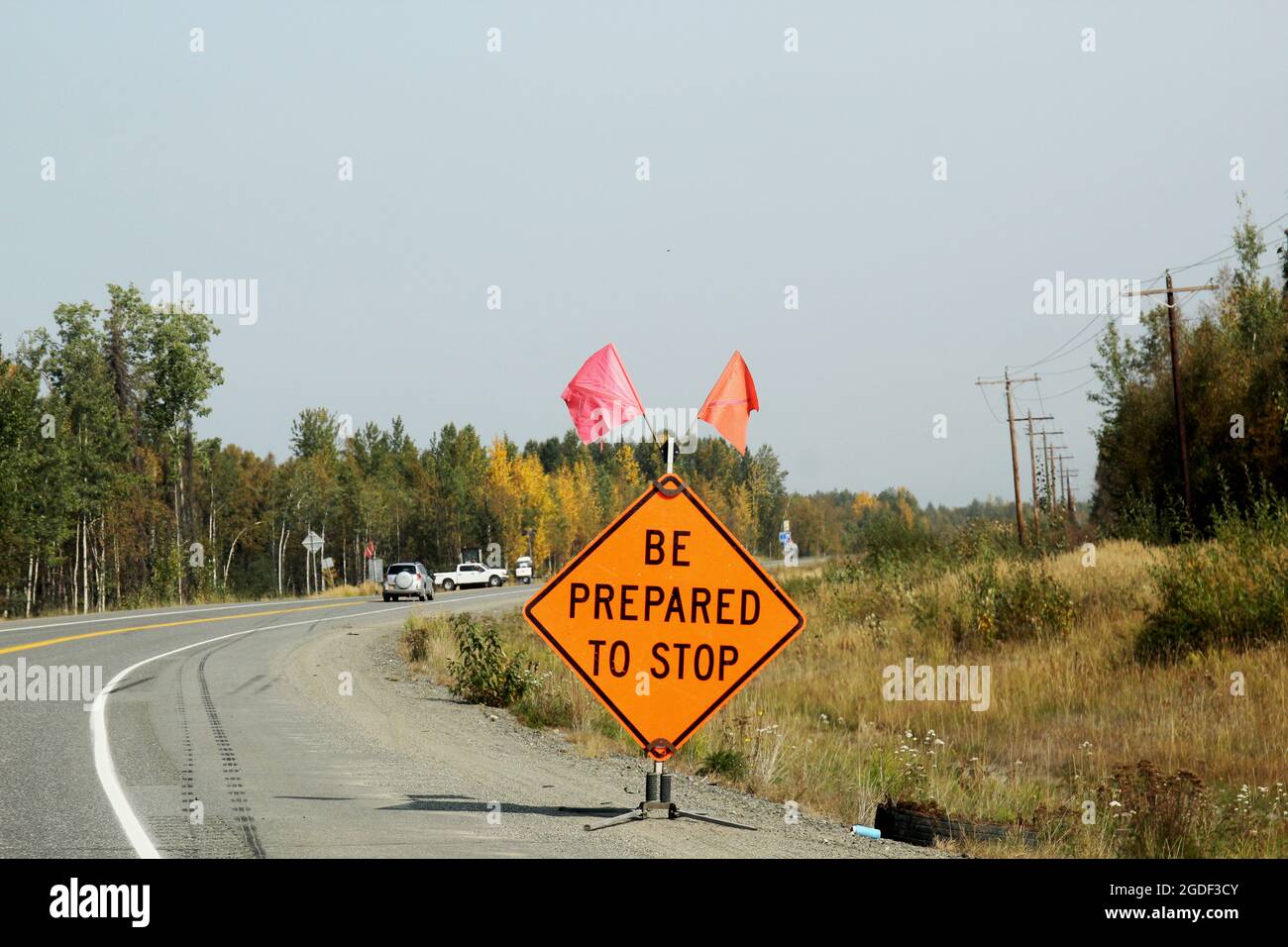 Amerikanisches Verkehrszeichen mit der Aufschrift 'be Prepared to stop' in orange mit einem roten Fähnchen und einem orangenen Fähnchen, Alaska, États-Unis. Banque D'Images