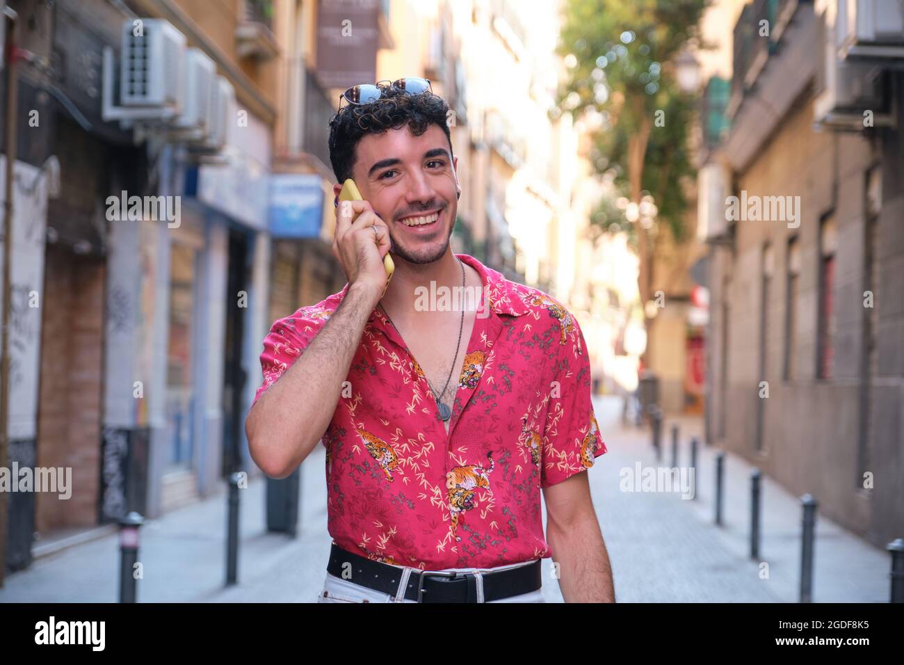 Jeune homme caucasien avec de longs ongles faux souriant et parlant au téléphone. Banque D'Images