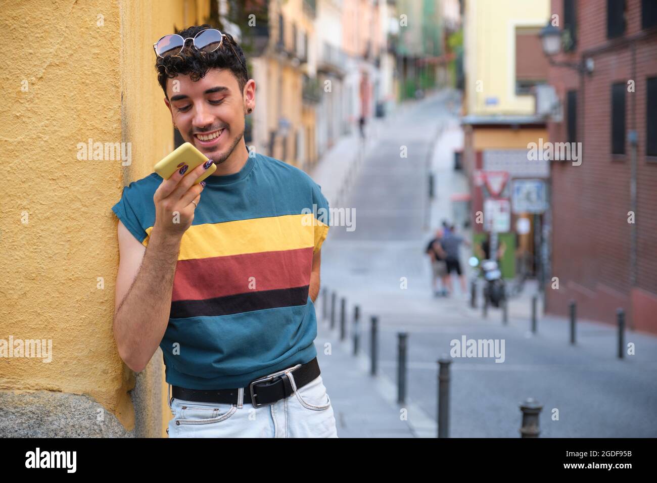 Jeune homme caucasien avec de longs ongles faux souriant et enregistrant une note audio. Banque D'Images