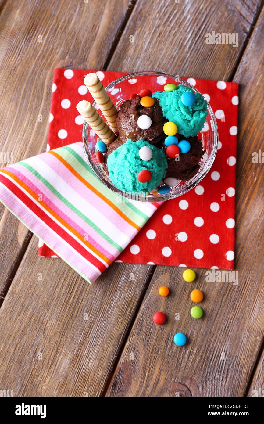 Glace au chocolat avec des bonbons multicolores et rouleaux de gaufrettes  dans bol en verre, sur fond de bois Photo Stock - Alamy