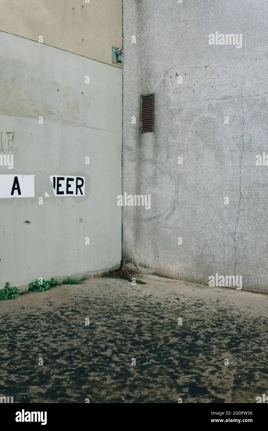 Plan vertical du coin du mur gris avec écriture déchirée et moulu partiellement couvert de terre Banque D'Images