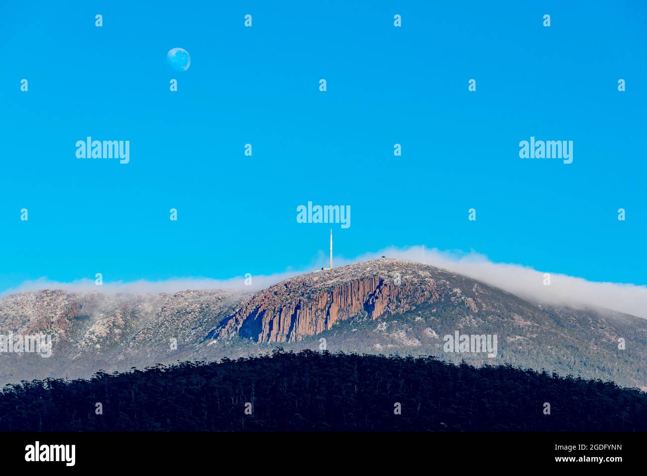 La lune étant encore en haut, une couverture de nuags matinaux se déroule au-dessus de Kunanyi (Mont Wellington) en direction de Hobart, capitale de la Tasmanie en Australie Banque D'Images