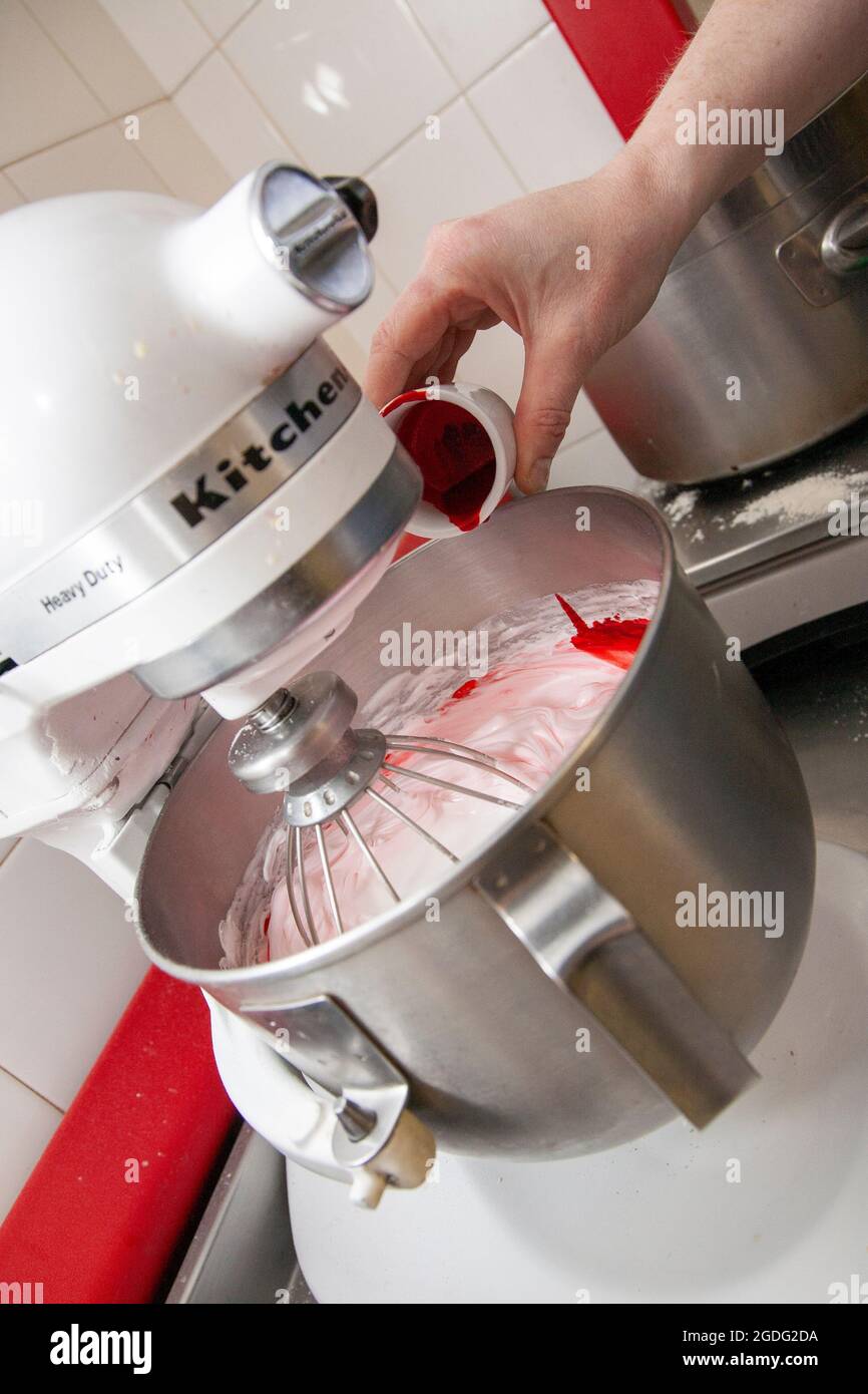 Ajouter de la coloration alimentaire rouge au blanc d'œuf pour créer la base des macarons. Banque D'Images