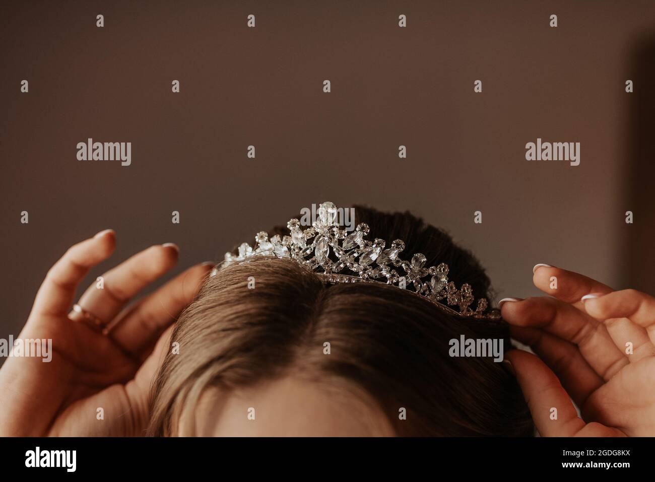 la jeune fille tient sur sa tête une couronne de tiara décorée de pierres précieuses, la jeune femme mariée redresse les accessoires sur sa tête et les oreilles Banque D'Images