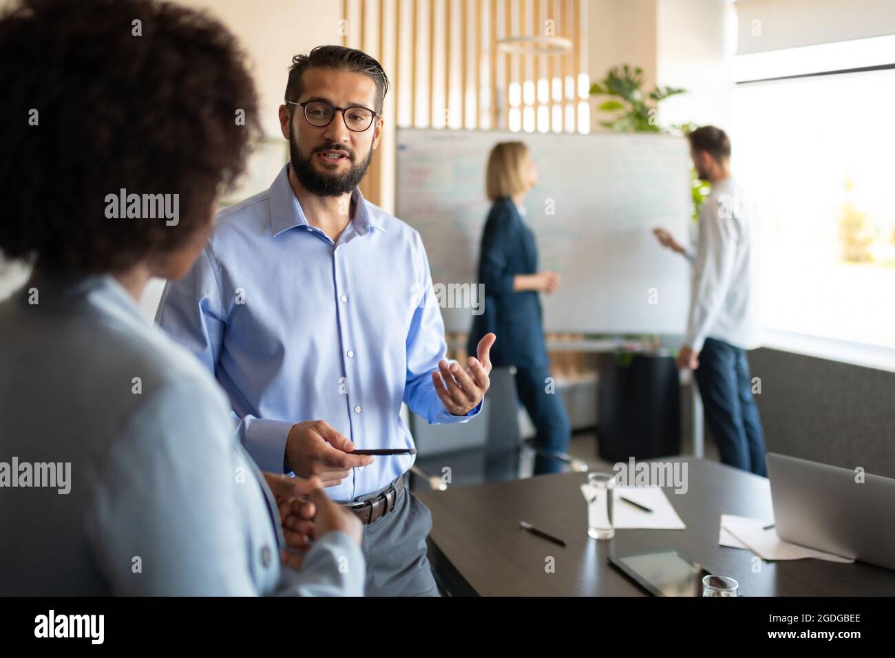 Responsable barbu parlant avec un collègue noir pendant le travail dans un bureau moderne Banque D'Images Responsable barbu parlant avec un collègue noir pendant le travail dans un bureau moderne Banque D'Images