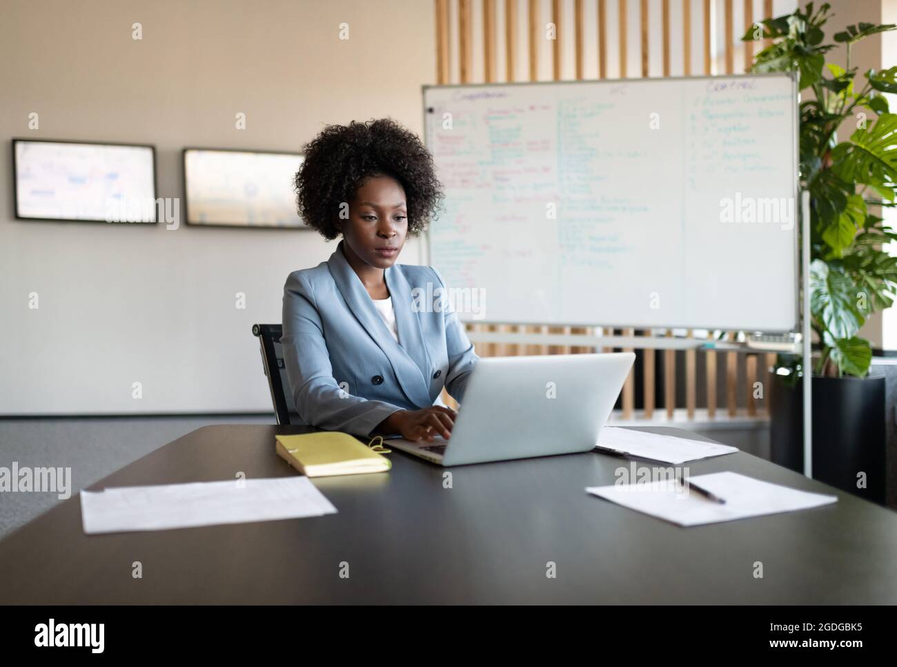 Une femme noire parcourt les données du netbook pendant le travail sur le projet au bureau Banque D'Images Une femme noire parcourt les données du netbook pendant le travail sur le projet au bureau Banque D'Images