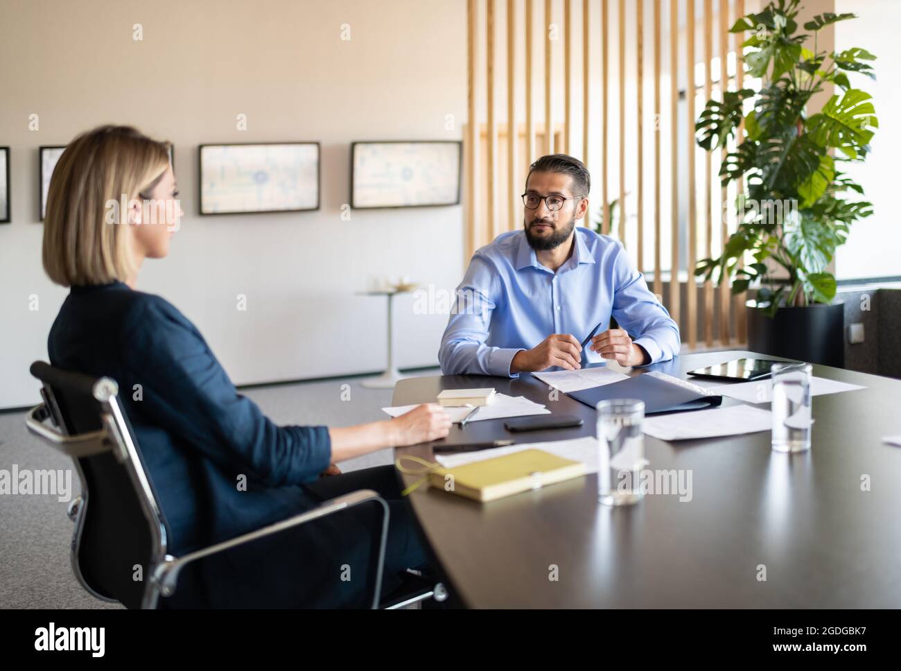 Homme d'affaires barbu interrogeant une femme recrutée à table au bureau Banque D'Images Homme d'affaires barbu interrogeant une femme recrutée à table au bureau Banque D'Images