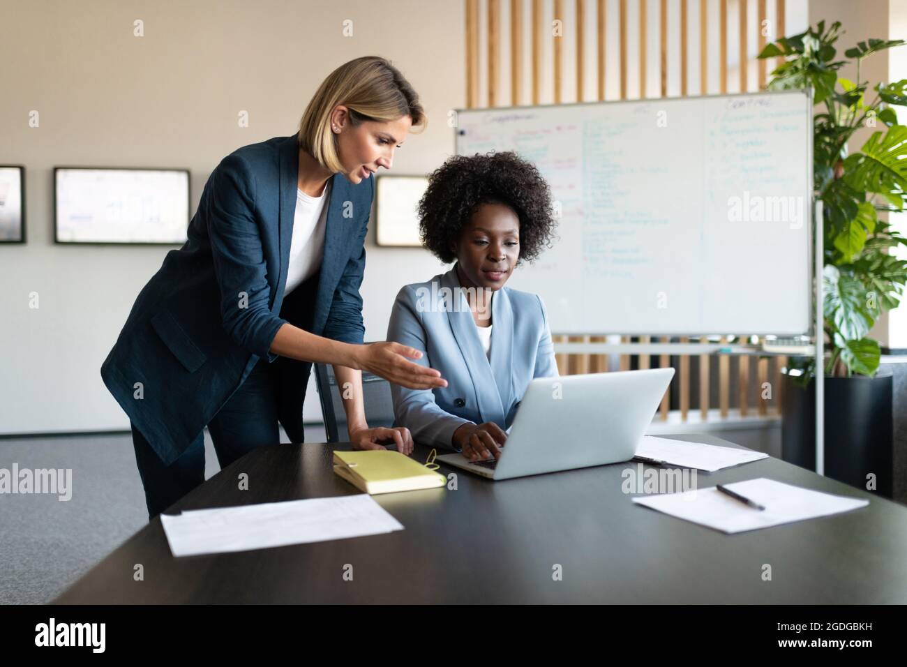 Collègues multiraciaux qui naviguent sur un ordinateur portable et discutent de données au bureau Banque D'Images Collègues multiraciaux qui naviguent sur un ordinateur portable et discutent de données au bureau Banque D'Images