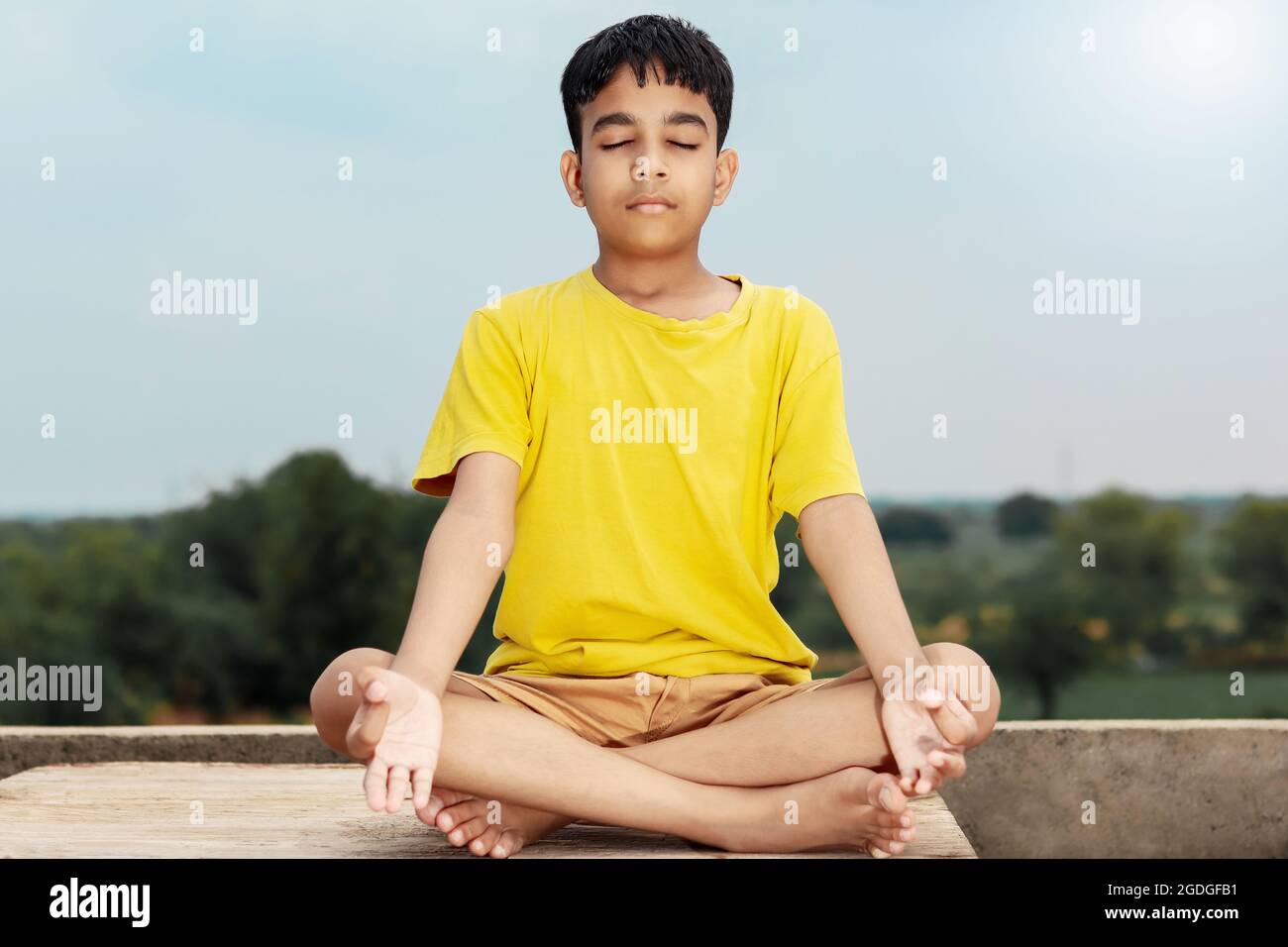 Un jeune enfant indien mignon faisant du yoga dans la posture de médiation. Banque D'Images