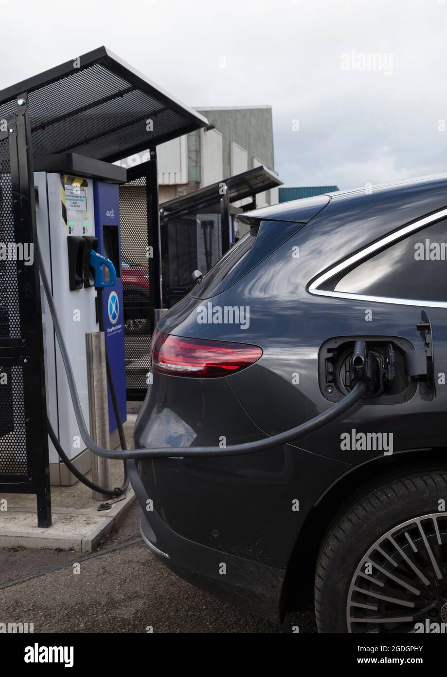 Voiture électrique au point de recharge public dans le parking. Banque D'Images