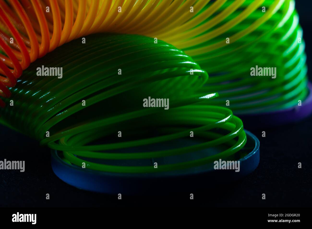 Gros plan d'un jouet de printemps arc-en-ciel slinky sur fond noir Banque D'Images