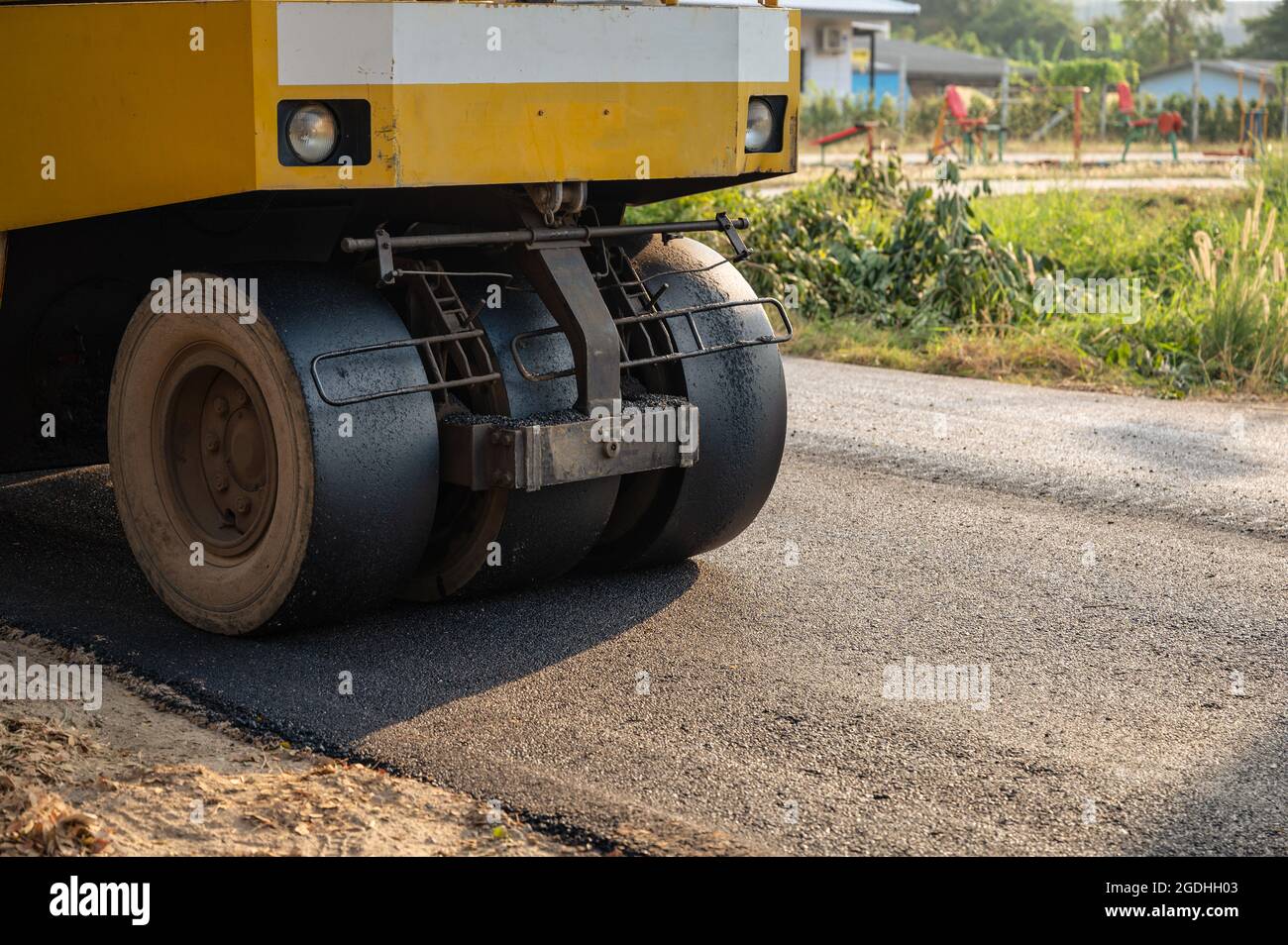 Compacteur de sol ou à vapeur jaune travaillant sur une route asphaltée sur le chantier de construction Banque D'Images