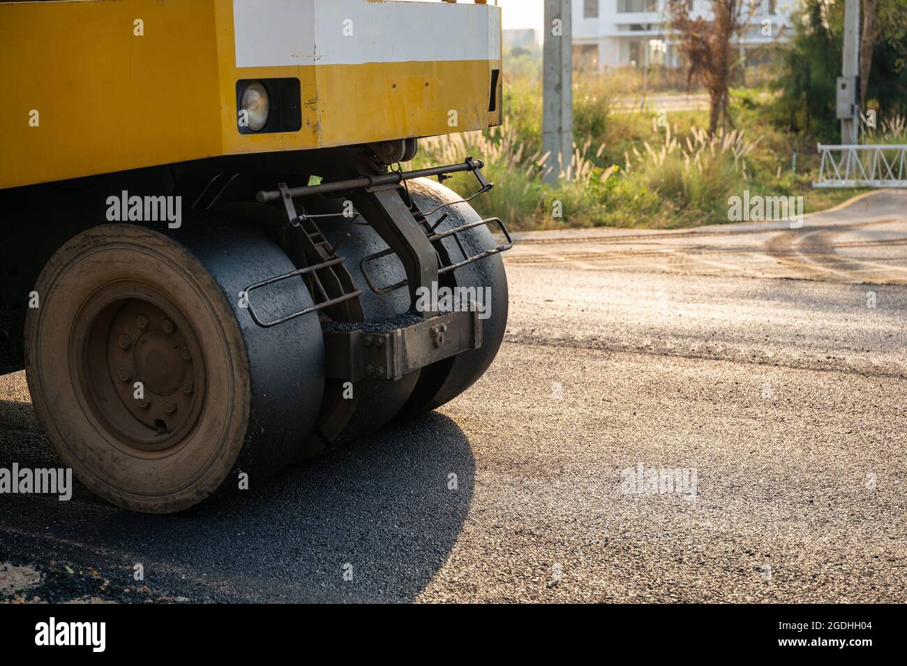 Compacteur de sol ou à vapeur jaune travaillant sur une route asphaltée sur le chantier de construction Banque D'Images