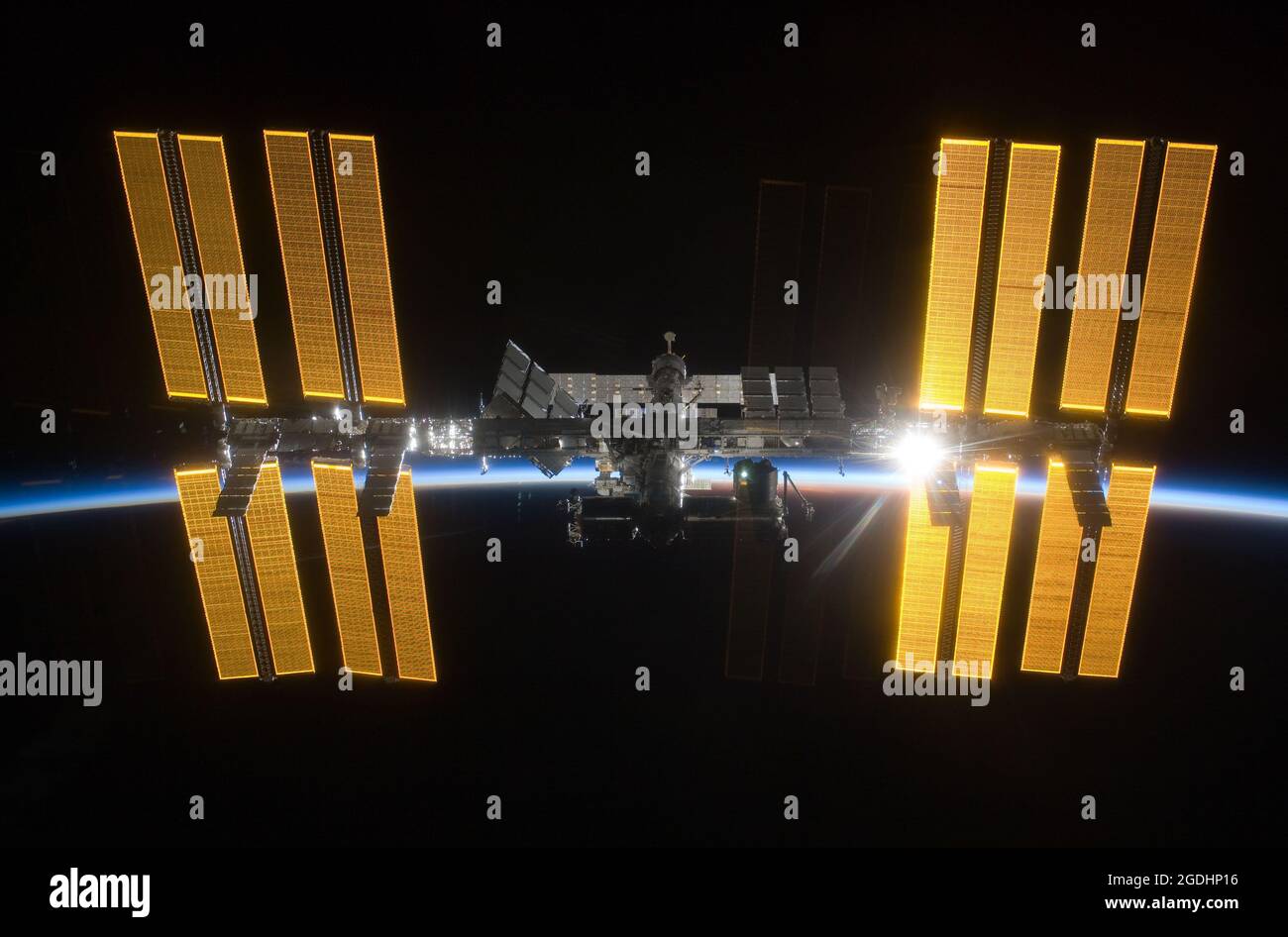 La Station spatiale internationale (ISS) vue contre la terre sombre avec le soleil levant derrière Banque D'Images