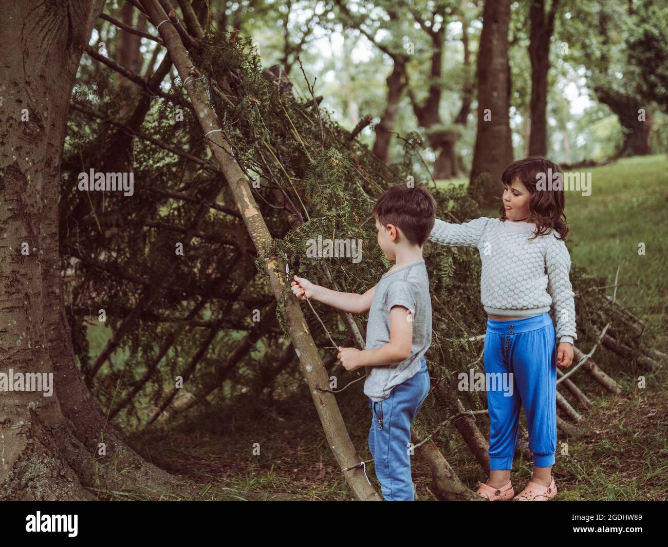 enfant caucasien dans une hutte faite de branches et de feuilles Banque D'Images