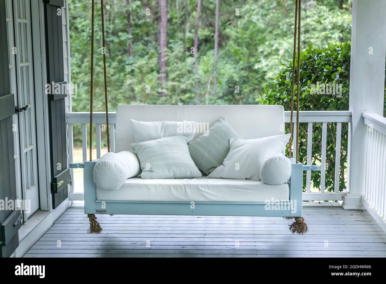 Une balançoire de lit d'extérieur luxueuse et classique peint un vert marin avec des coussins profonds blancs Banque D'Images