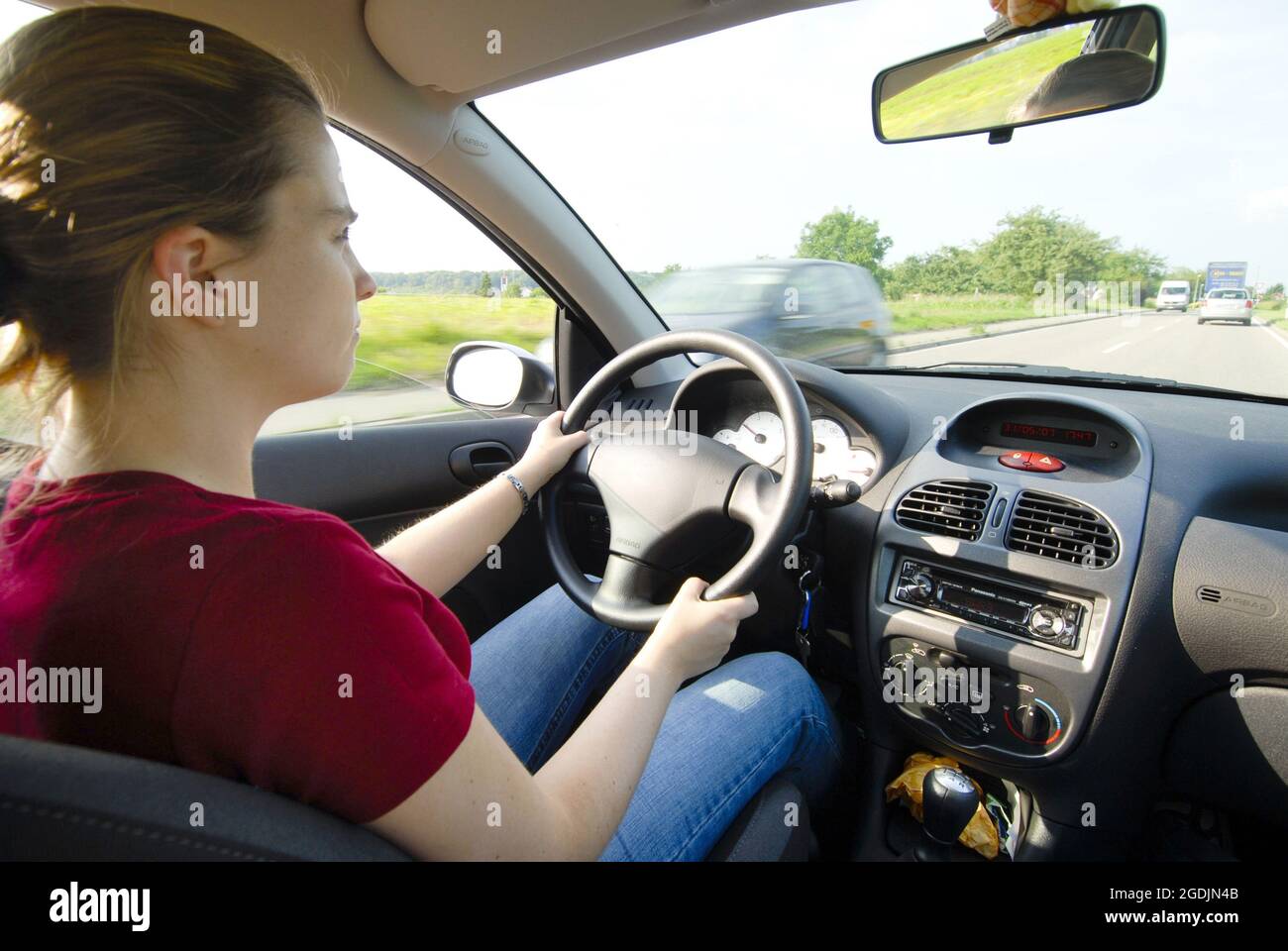 Jeune conducteur dans la voiture, volant avec airbag, rétroviseur, Allemagne Banque D'Images