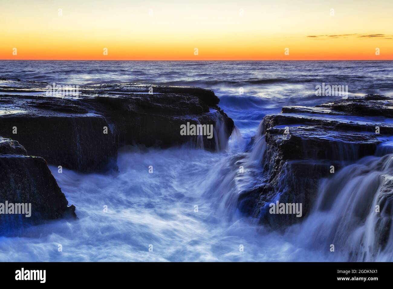 Des rochers humides autour de la tranchée côtière au large de la plage de Narrabeen à Turimetta Head of Sydney Northern Beaches et Pacific Ocean pittoresque lever de soleil. Banque D'Images