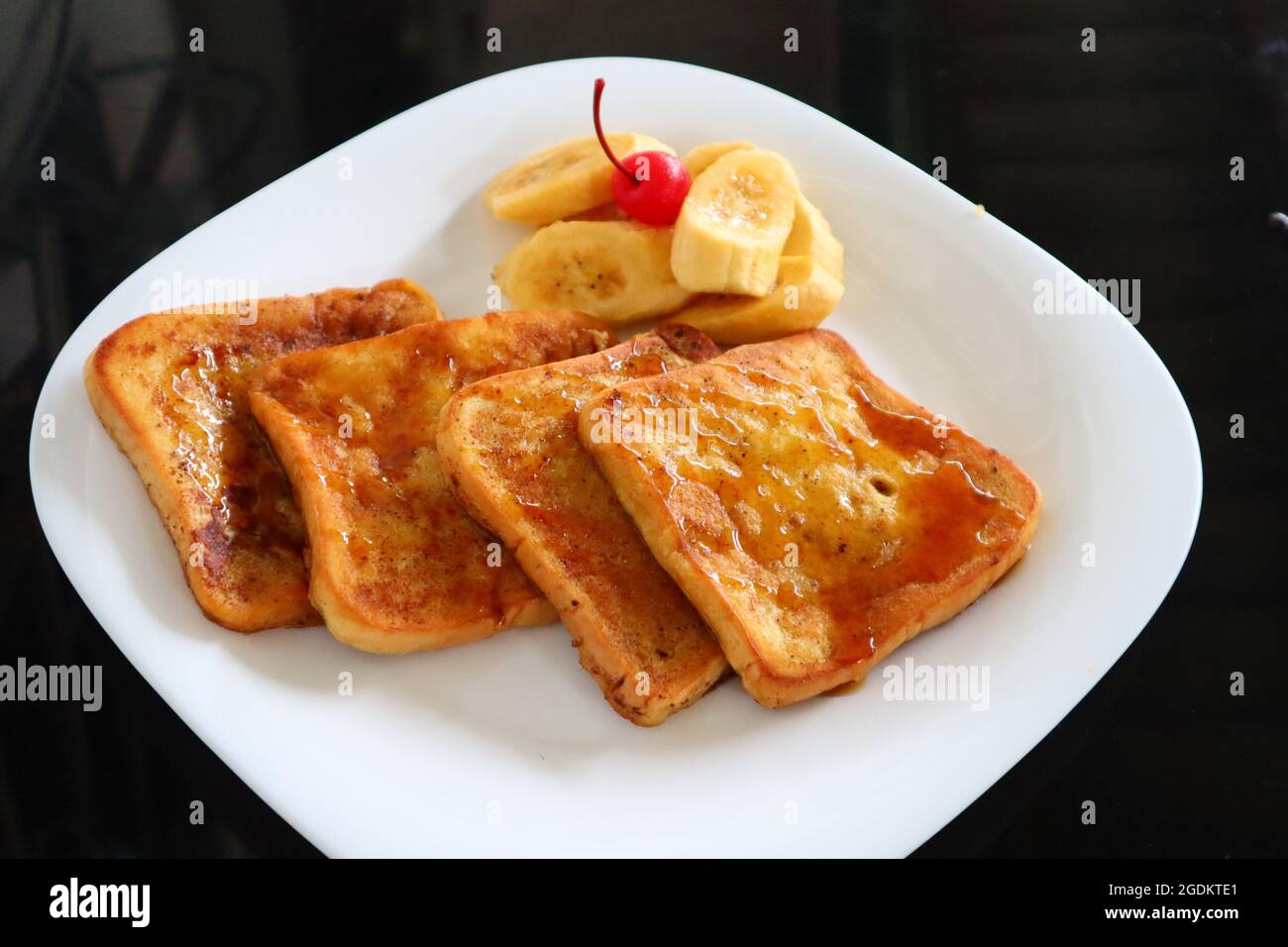 Pain grillé au miel et fruits dans une assiette blanche Banque D'Images