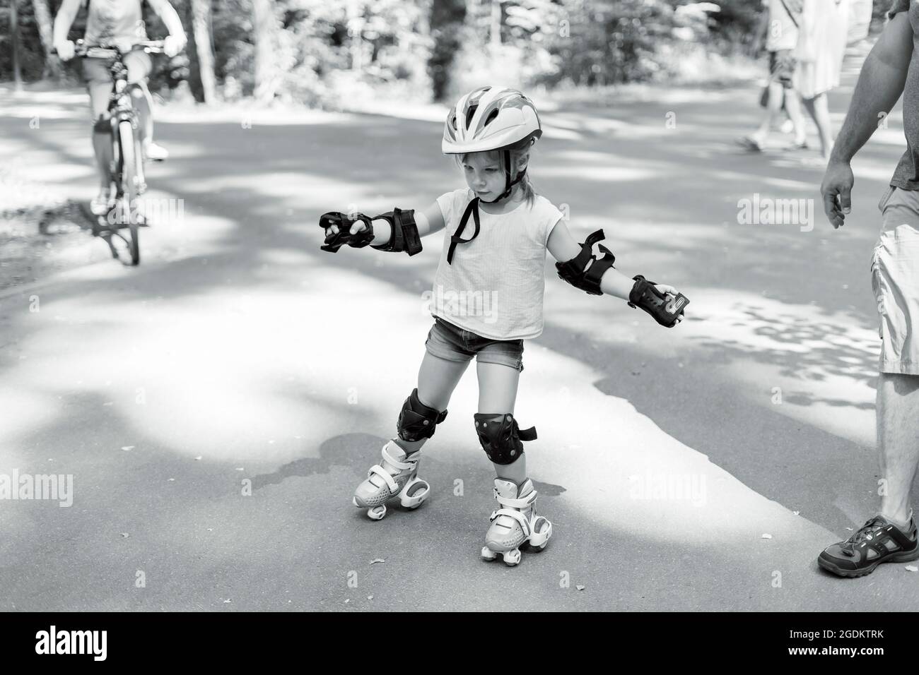 petite fille est en roller dans le parc. bébé dans des vêtements de sport  protecteurs. photo noir et blanc Photo Stock - Alamy