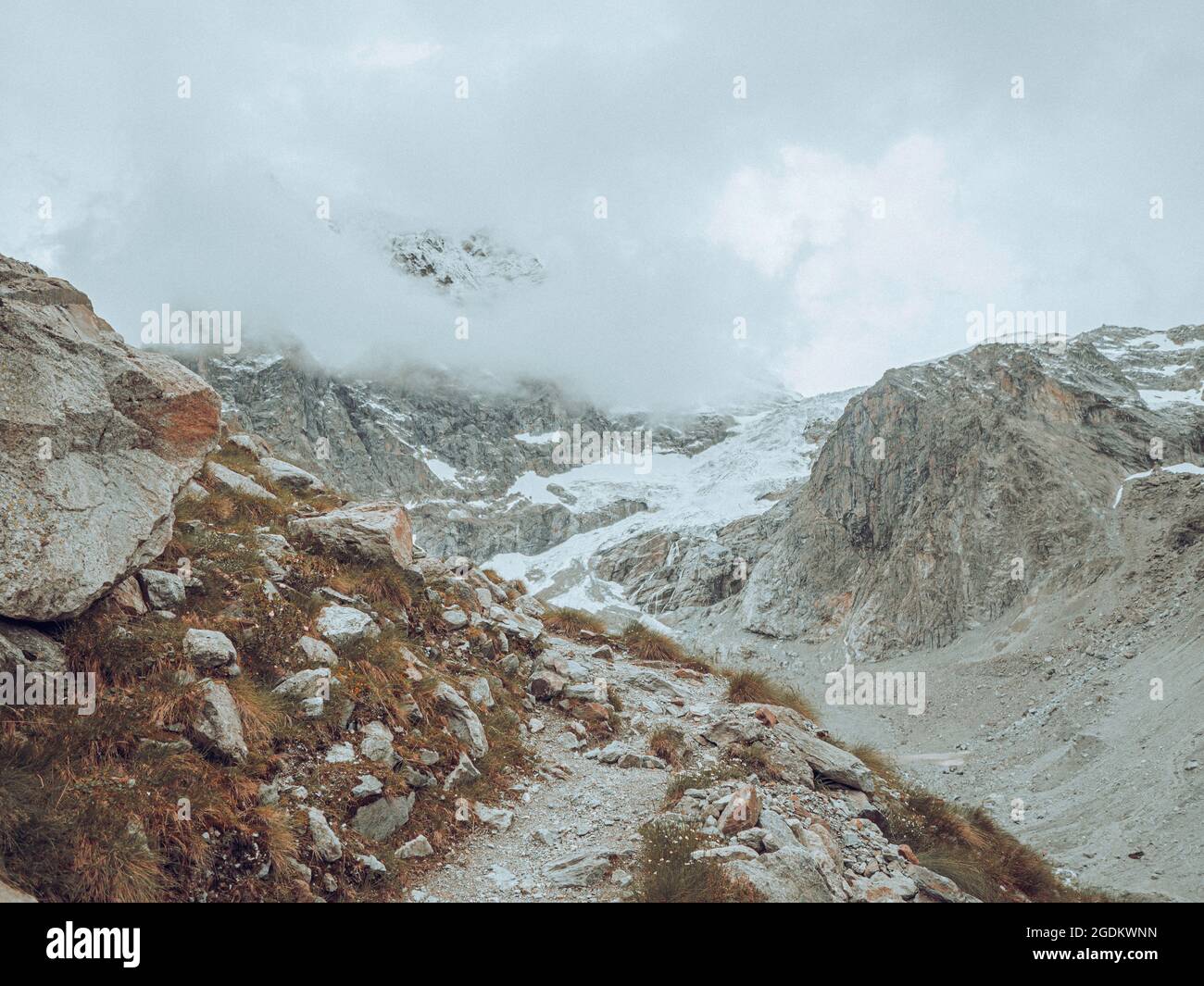 vue de drone sur un glacier alpin désolaté entouré de montagnes et de rochers enneigés et de pics. Banque D'Images