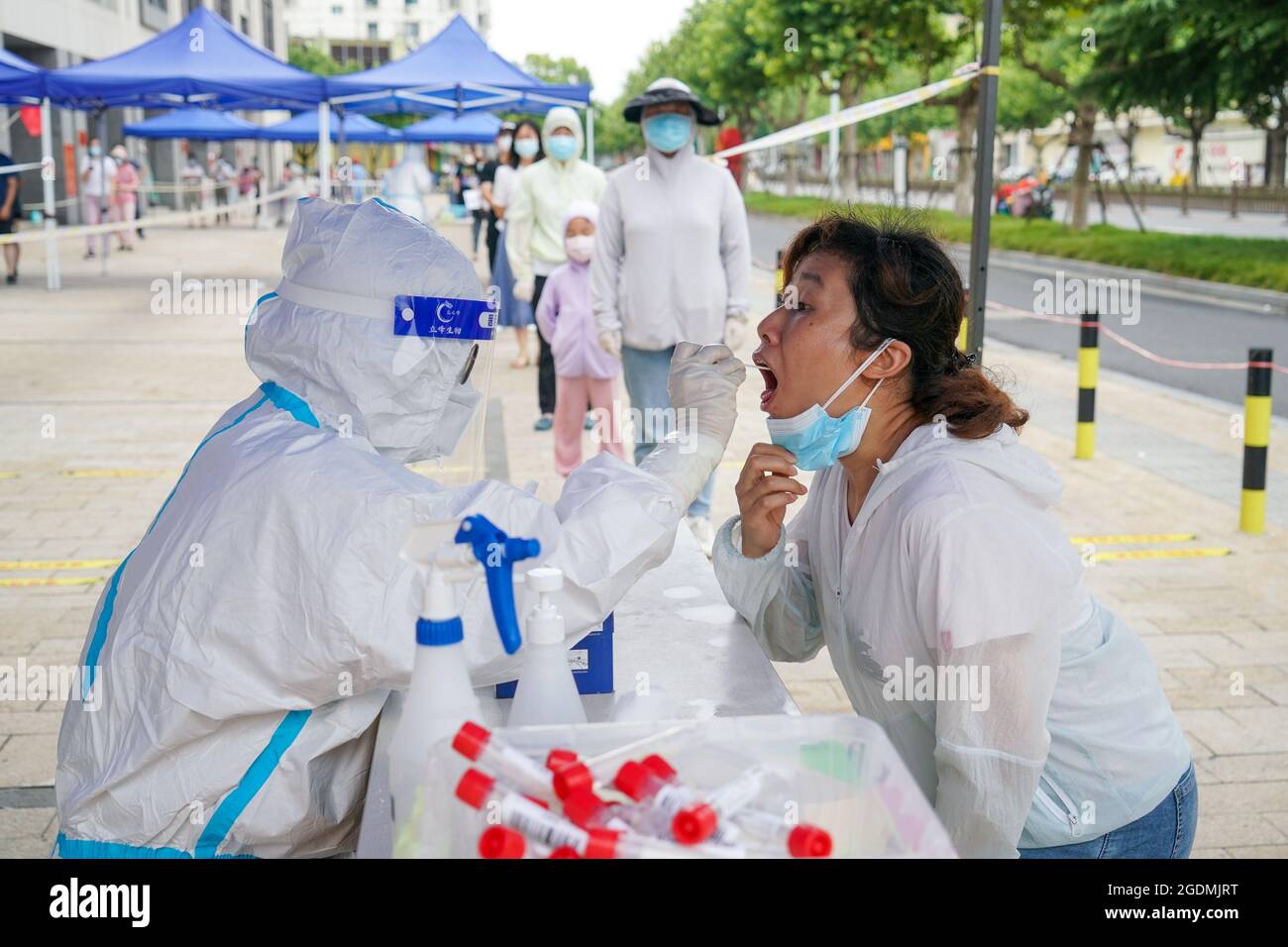 Yangzhou, province chinoise du Jiangsu. 14 août 2021. Un travailleur médical prélève un échantillon d'écouvillon de gorge auprès d'une femme sur un site de test d'acide nucléique à Yangzhou, dans la province de Jiangsu, dans l'est de la Chine, le 14 août 2021. La ville de Yangzhou a lancé samedi un nouveau cycle de tests d'acides nucléiques de masse dans des zones clés. Credit: Li Bo/Xinhua/Alay Live News Banque D'Images