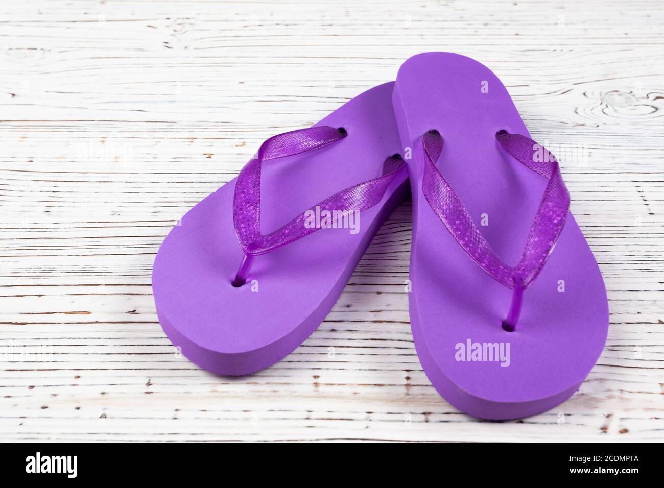 pantoufles en caoutchouc violet sur fond de bois blanc Banque D'Images