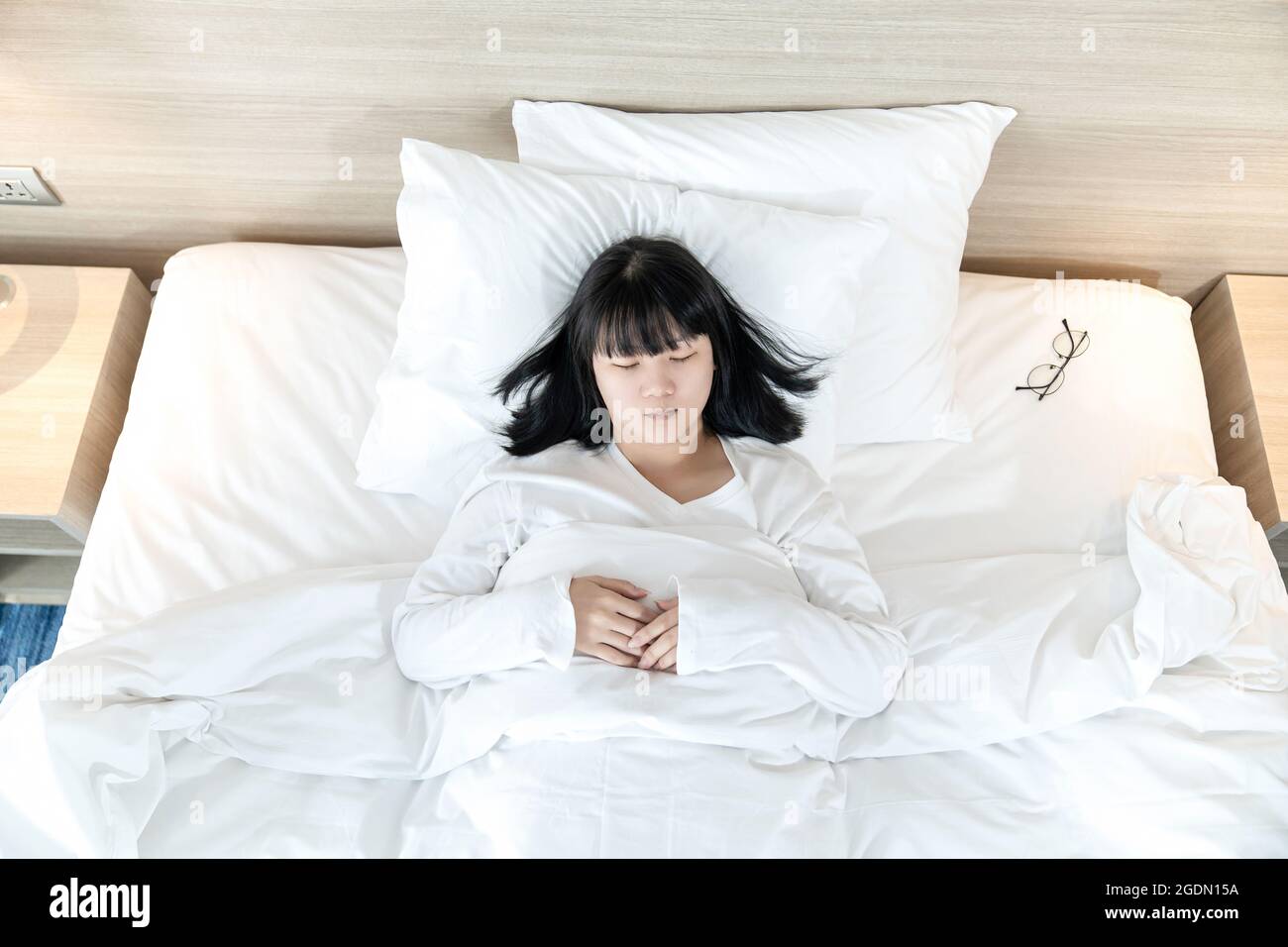 Femme asiatique dort sur un lit blanc après avoir épuisé et essayé toute la journée. Banque D'Images