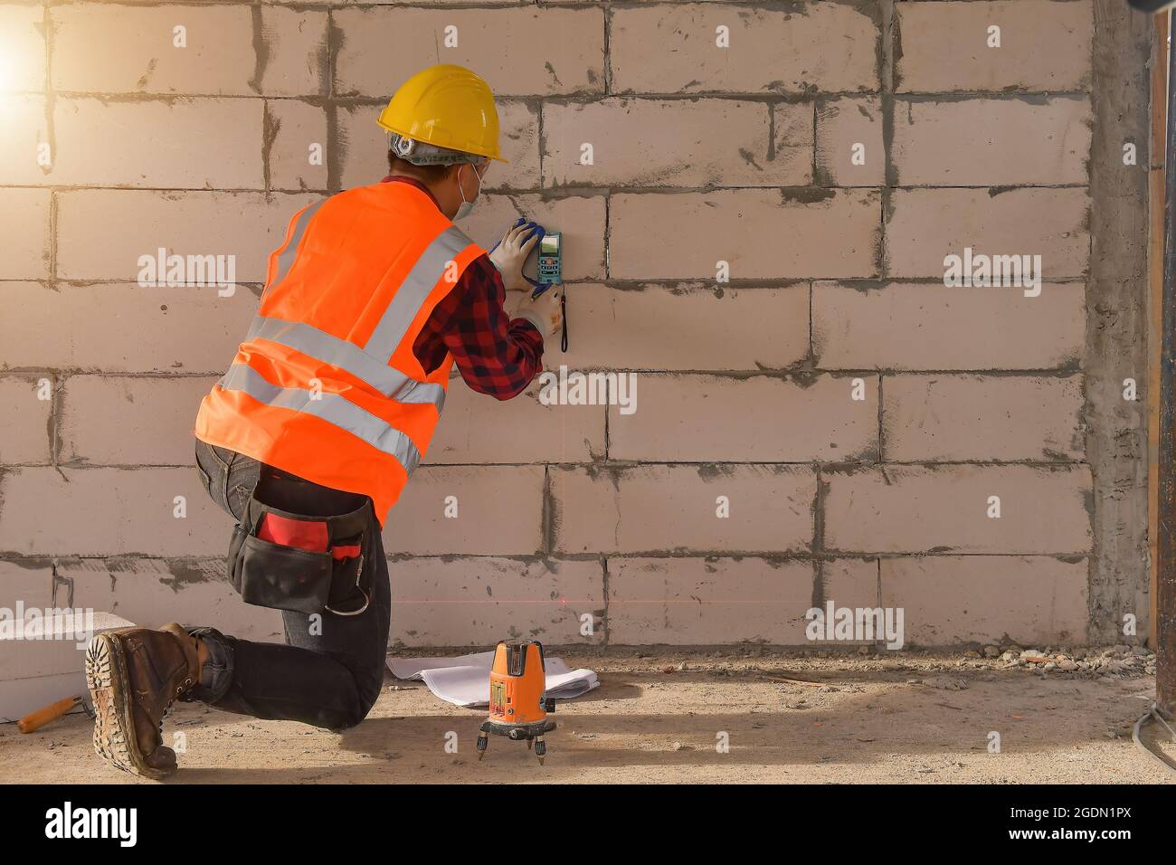 Technicien avec niveau de mesure laser pendant le travail, ouvrier de  construction mesurant le faisceau de support allumé pendant le coucher du  soleil Photo Stock - Alamy