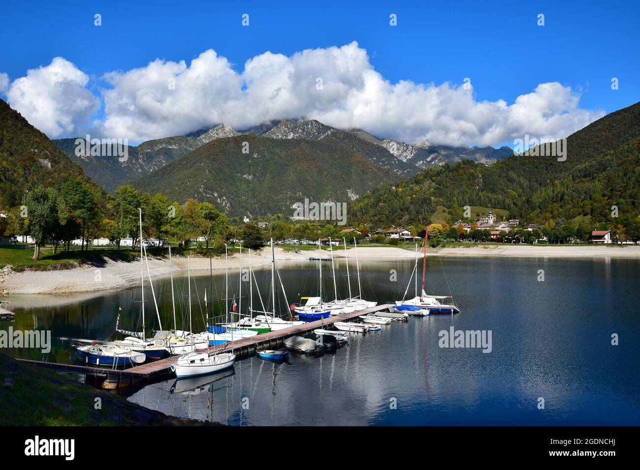 La petite ville de Pieve di Ledro, le magnifique lac de Ledro et les montagnes environnantes lors d'une journée d'automne claire. Une étape d'atterrissage en bateau et quelques bateaux. Trentin Banque D'Images