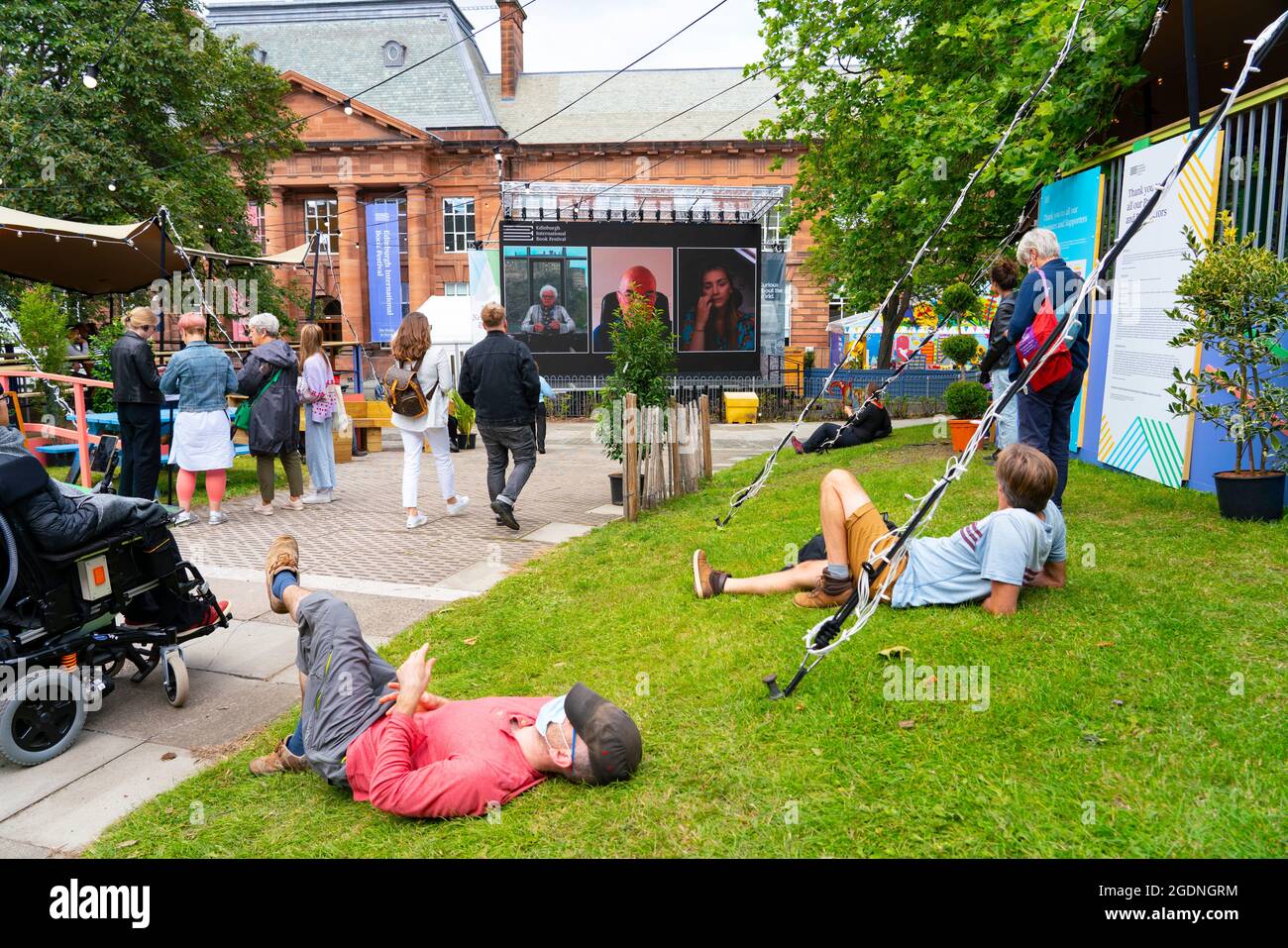 Édimbourg, Écosse, Royaume-Uni. 14 août 2021. Vues sur le jour d'ouverture du Festival International du livre d'Édimbourg à un nouveau lieu au Edinburgh College of Art. Ayant quitté son ancien site aux jardins de Charlotte Square, le Festival du livre s'est déplacé dans une cour au Edinburgh College of Art. Le nombre de visiteurs était probablement faible à l'heure du déjeuner en raison de de nombreux événements sont déplacés vers des diffusions en ligne. Photo : le grand écran de la cour montre des interviews en direct avec des auteurs. Iain Masterton/Alamy Live News. Banque D'Images